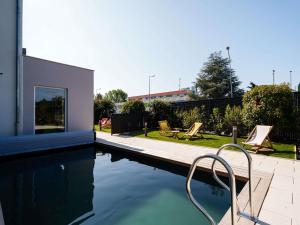 a swimming pool with two chairs next to a house at ibis budget Strasbourg Sud Illkirch in Geispolsheim