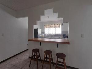 una cucina con due sgabelli e un bancone con finestra di River House San Jose a Sarapiquí Altre 19 foto