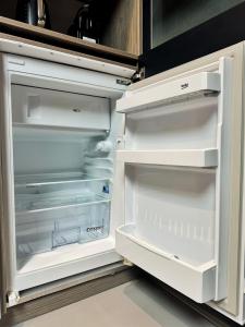 an empty refrigerator with its door open in a kitchen at L'annexe 3 - Cosy studio Dole in Foucherans