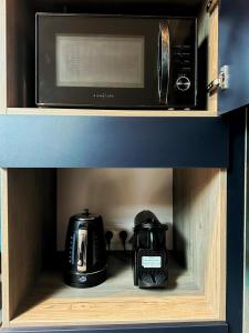a microwave and a toaster sitting on a shelf at L'annexe 3 - Cosy studio Dole in Foucherans