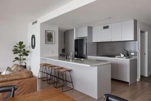 een keuken met witte kasten en een bar met krukken bij The Outlook - 2 bed option in Newcastle