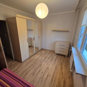 ein Schlafzimmer mit einem Schrank, einer Kommode und einem Spiegel in der Unterkunft Mieszkanie Kapitana Pałaca in Serock