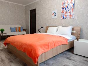 una camera da letto con un letto con una coperta arancione di 11 Microragion ad Aqtöbe