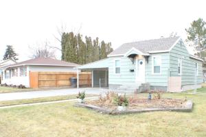 a blue house with a fence and a yard at Sage Cottage in American Falls