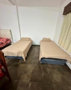 two beds in a room with a tiled floor at Sueños de Mar in Mar del Tuyú +2 photos