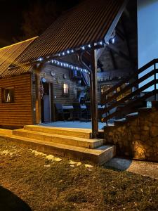 a wooden cabin with a porch with lights on it at Kuća za odmor Ema in Gospić