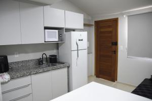 a kitchen with white cabinets and a white refrigerator at Loft 01 in Tubarão