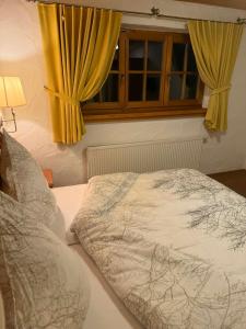 a bedroom with a bed and a window with yellow curtains at JOHN'S Pension in Saarwellingen