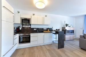 a kitchen with white cabinets and a table in a room at Ferienwohnung Sonnensegler in Juliusruh