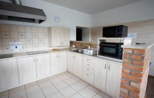 a kitchen with white cabinets and a black microwave at Noclegi in Ruda Śląska