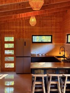 a kitchen with a refrigerator and a table with stools at Casa Oregon Pucura in Traitraico