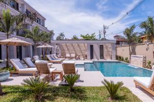 a swimming pool with chaise lounges and chairs near a building at Solena Hotel in Camburi +62 photos