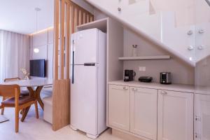 a kitchen with a white refrigerator and a table at Solena in Camburi