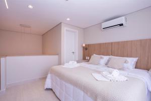 a bedroom with a large white bed with towels on it at Solena in Camburi +65 photos