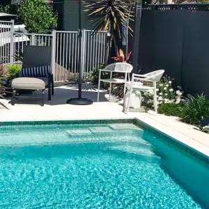 - une piscine avec une chaise et un banc à côté dans l'établissement Courtyard Pool Studio Private Luxe Retreat, à Coal Point