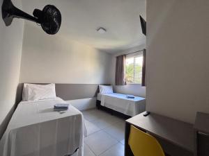 a room with two beds and a table and a window at Hotel Master Plaza Formiga in Formiga