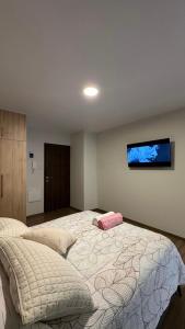 a bedroom with a large bed with a tv on the wall at Suite Prado-PC0n Garant1a in Cochabamba
