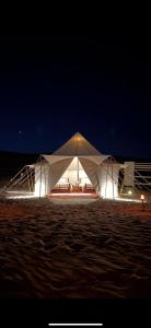 a large white tent on the beach at night at Desert waves camp in Bidiyah