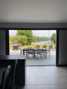 une terrasse avec une table et des chaises ainsi qu'une grande fenêtre. dans l'établissement Chambres d'hôtes bord de Saône, à Lamarche-sur-Saône