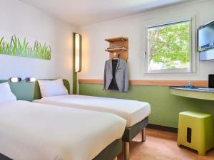 une chambre d'hôtel avec deux lits et un lavabo dans l'établissement Ibis Budget Versailles Coignieres, à Coignières