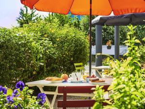 une table avec de la nourriture dessus sous un parasol dans l'établissement Ibis Budget Versailles Coignieres, à Coignières