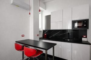 eine Küche mit einem schwarzen Tisch und 2 roten Stühlen in der Unterkunft Maison Valentino in Mailand + 6 Fotos