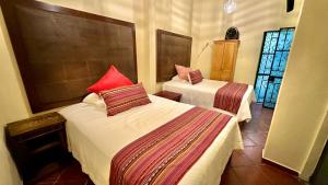a bedroom with two beds with red pillows on them at Casona Bartolome in Morelia