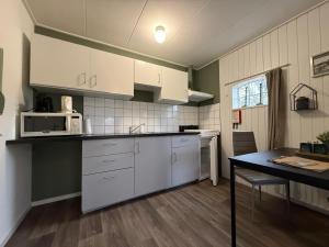 a kitchen with white cabinets and a table in it at De Deelderij in Schoonloo