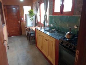 a kitchen with a stove and a sink and a table at Alojamiento La Oti in Tilcara
