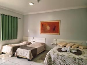 a bedroom with two beds and a green curtain at Hotel Pousada Marra in Catalão