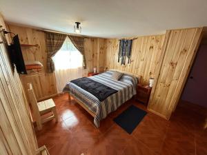 une chambre avec un lit dans une pièce aux murs en bois dans l'établissement Hostal Aves del Sur Coñaripe, à Panguipulli