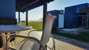 una sedia di vimini seduta accanto a un tavolo su un ponte di Cabana Raio de Sol RS a Osório Altre 25 foto
