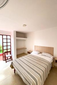 een slaapkamer met een groot bed en een stoel bij LAS PALMERAS HOSTAL in Barranca