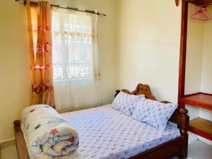 a bedroom with a bed and a window with curtains at KidotuiVillaHome in Arusha