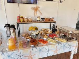 een tafel met een heleboel verschillende soorten voedsel erop bij Pousada Ponta dos Corais in Guarujá