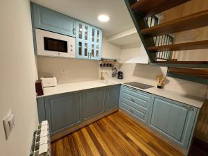 a kitchen with blue cabinets and a microwave at CASINA La RIBERA in Cudillero