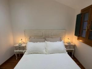 a bedroom with a white bed with two lamps on tables at CASINA La RIBERA in Cudillero