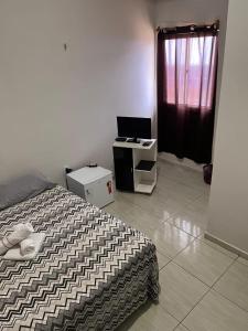 a bedroom with a bed and a desk with a laptop at Pousada e Hostel Santos in Barreirinhas