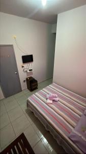 a bedroom with a bed with a pair of pink shoes on it at Pousada e Hostel Santos in Barreirinhas
