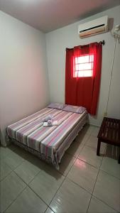 a bed in a room with a red window at Pousada e Hostel Santos in Barreirinhas