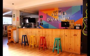 a bar with four colorful stools in a restaurant at Magic Packer Hostel in Cusco