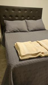 un letto con testiera nera e lenzuola e cuscini grigi di Edificio-Pellegrini PA a Bragado