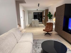 a living room with a couch and a chair and a television at Casa Blanc - Coastal Triplex in Blankenberge