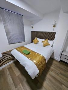 a bedroom with a large bed with gold sheets and pillows at Union House in Stratford-upon-Avon