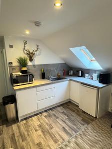 eine Küche mit weißen Schränken und einer Spüle und einem Fenster in der Unterkunft An Cuiltheann Apartment in Turriff