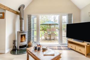 ein Wohnzimmer mit Kamin und einem Tisch mit Sonnenschirm in der Unterkunft 1 Bed in Dickleburgh oc-m33974 in Dickleburgh