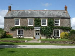 een oud bakstenen huis met twee banken ervoor bij 7 Bed in Shebbear oc-w33731 in Black Torrington