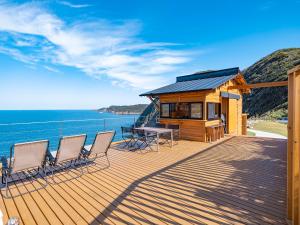 a house with chairs and a table on a deck at On The Cliff in Karatsu