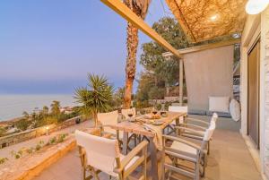 eine Terrasse mit Tisch und Stühlen und dem Meer in der Unterkunft Thomais 2-Villa Stone Estate with Pool & Sea Views in Agia Pelagia