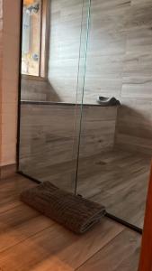 a glass shower door with a rug on a wooden floor at Espaço RAVI 1 in Monte Verde +16 photos